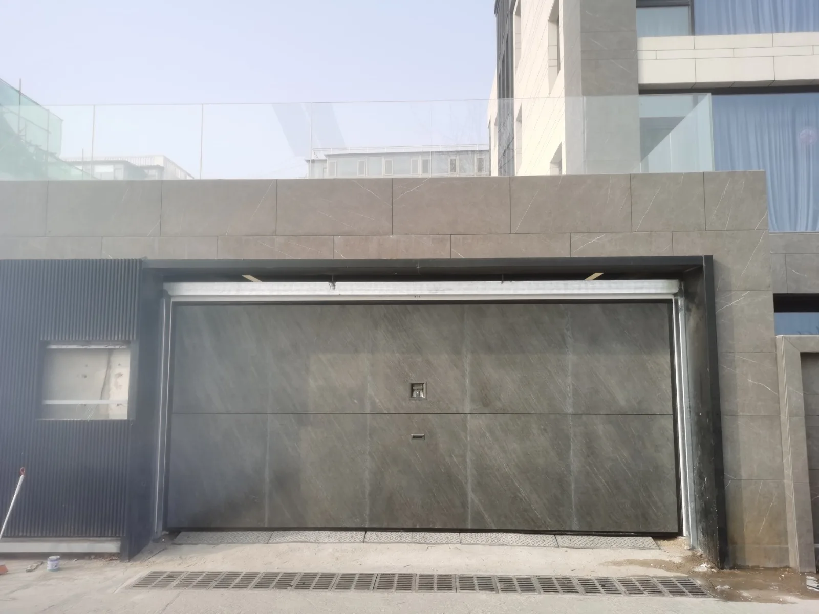 Puerta Overlap de acabado gris integrada en una fachada contemporánea